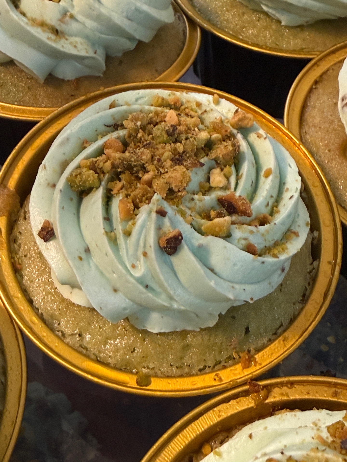 Pistachio mini cake with blue buttercream swirl and crushed pistachios