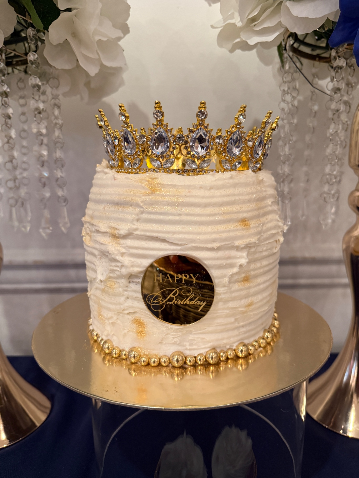 White ruffled buttercream cake with jeweled gold crown topper