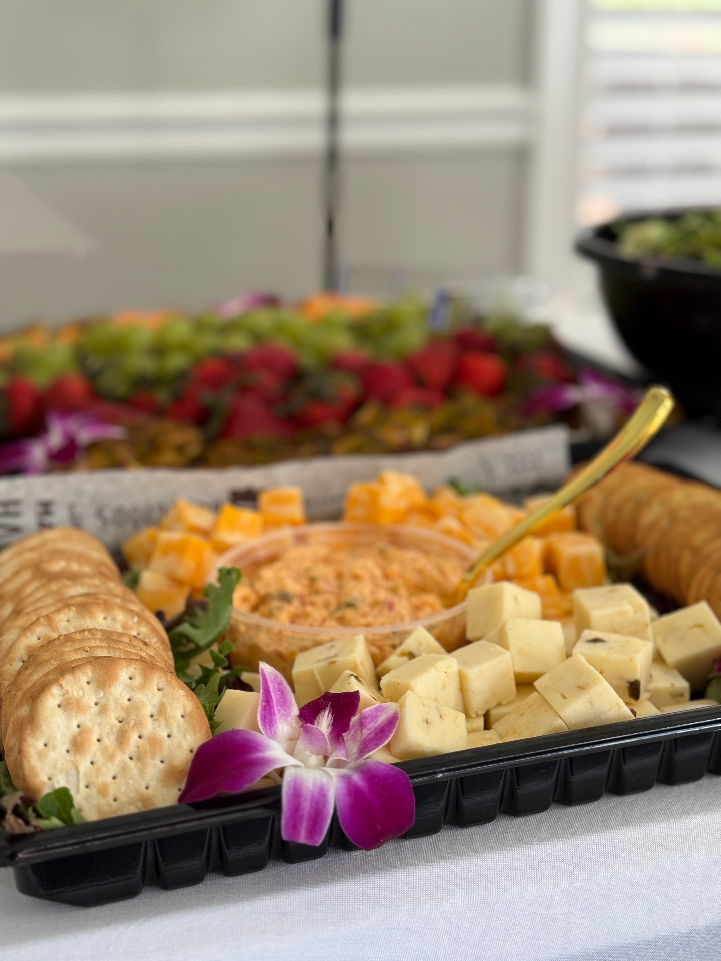 Charcuterie board with cheeses, crackers, pimento dip, and fresh fruit